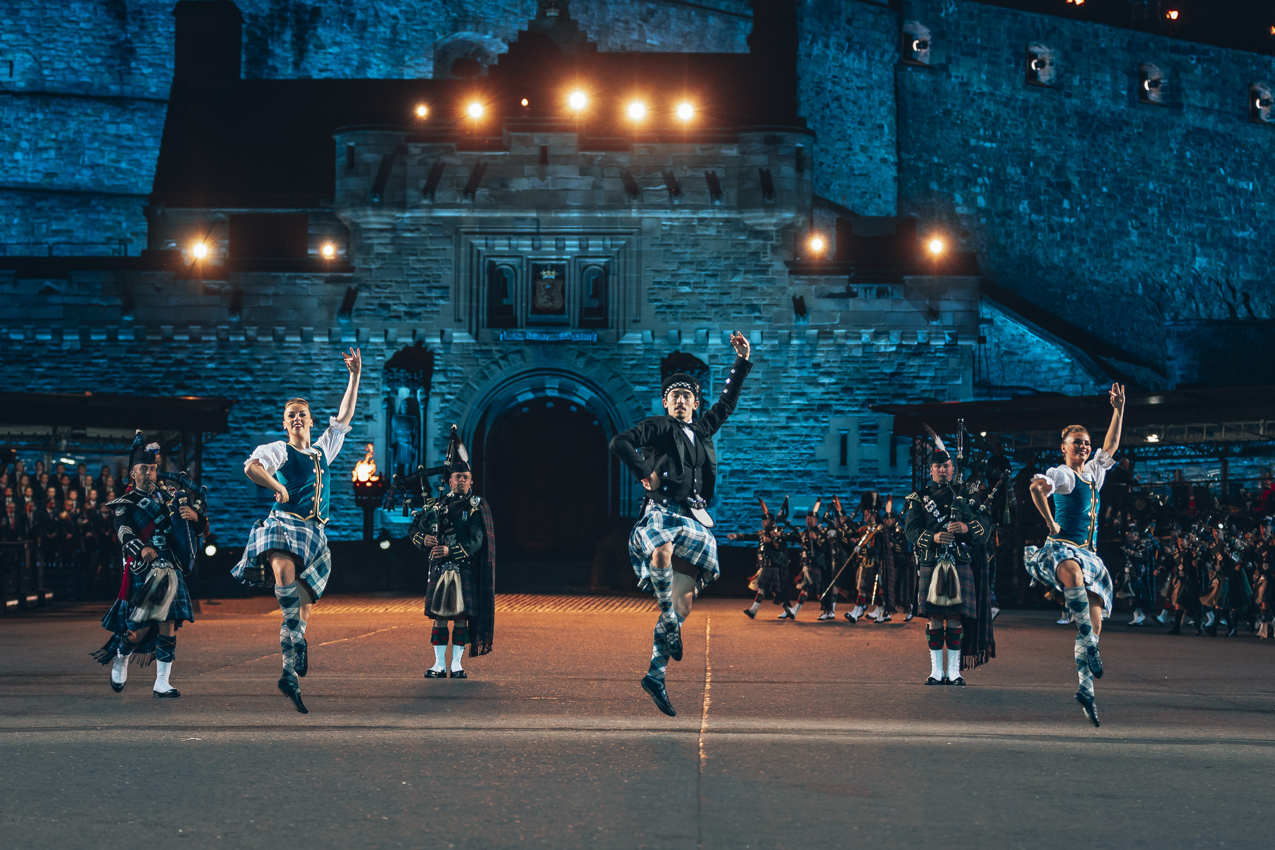 Image shows Highland Country dancers and RAF Pipe and Drums band performing outside Edinburgh Castle. 